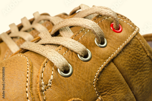 close-up view of lacing on tan color, leather sneakers isolated on white background.