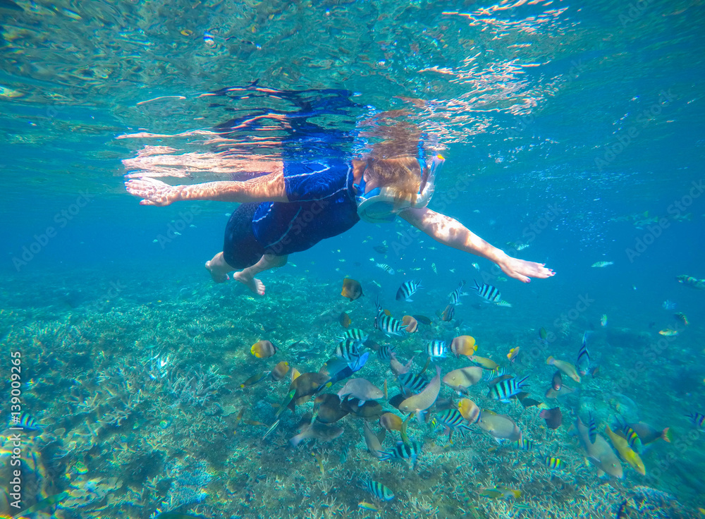 Snorkel and coral fishes underwater in swimming costume and full-face mask