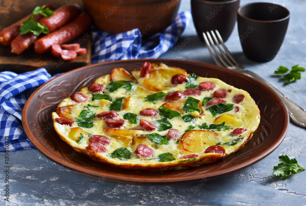 Omelet with spinach, cheese and Bavarian sausages on a concrete background