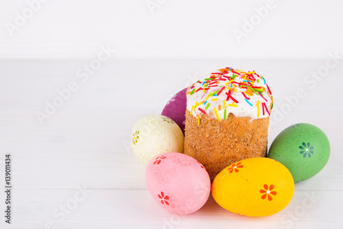 Easter cake with colorful eggs on white wooden background
