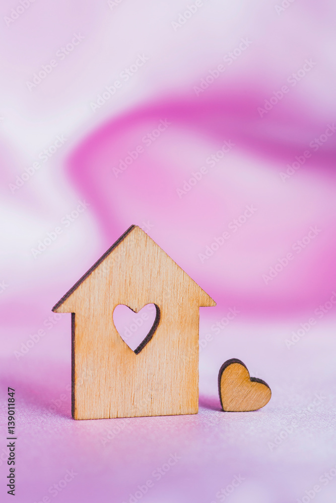 Φωτογραφία Wooden house with hole in form of heart on pink satin fabric