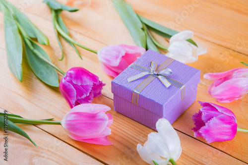 Bouquet of tender pink tulips with gift box on light wooden background