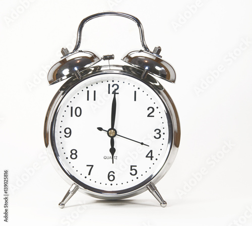 Old fashioned silver alarm clock against a white background