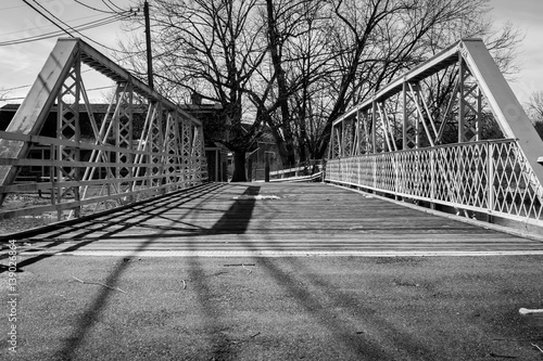 Steel bridge walkway on sunny day. Wooden and steel bridges with natural light and shadow. Outdoor park bridge footpath walkway. Tree and branch background. Nature and industrial background design. 