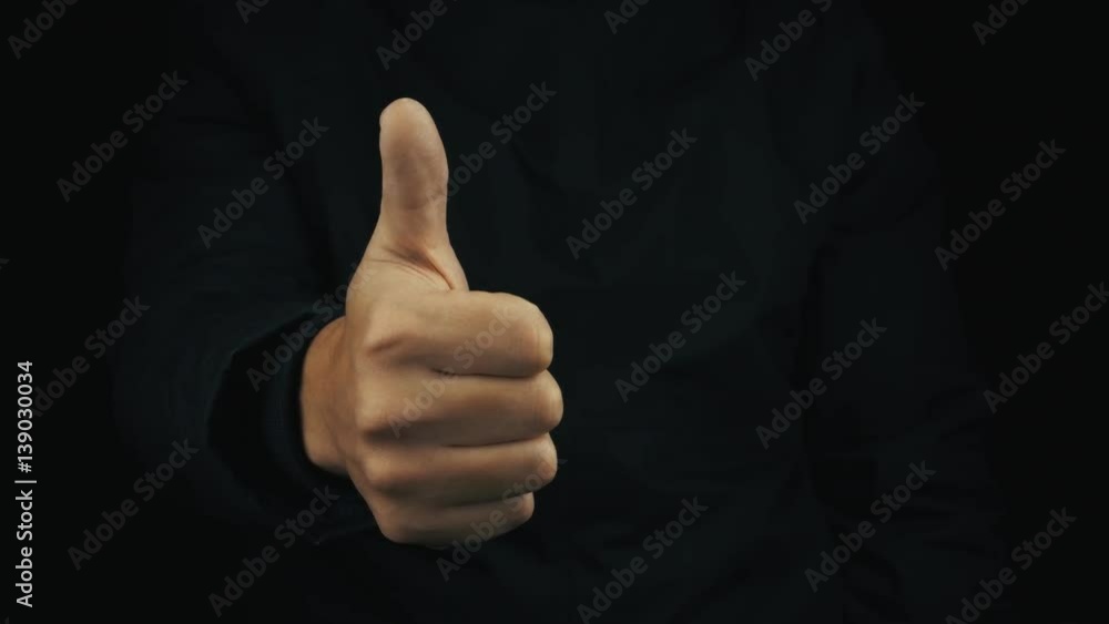 Caucasian male hand in long sleeve jacket making positive thumbs up finger gestures, turn them down on black background, close up isolated Caucasian male hand in long sleeve jacket making positive thumbs up finger gestures, turn them down on black background, close up isolated