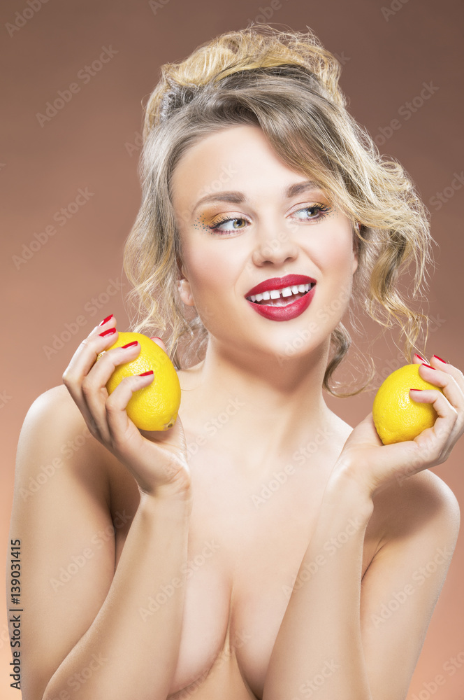 Sensual Fruit Series. Portrait of Alluring Sexy Caucasian Blond Girl With Two Lemons. Posing Against Orange Background. Sensual Fruit Series. Portrait of Alluring Sexy Caucasian Blond Girl With Two Lemons. Posing Against Orange Background.