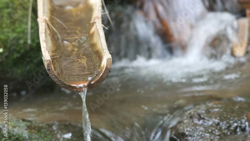 water is flowing from the bamboo tube in the tropical stream photo