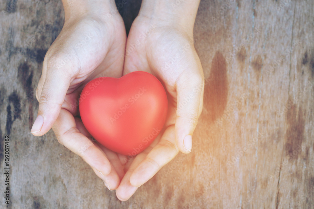 Female hands giving red heart overhead of wooden planks in the morning light. Filtered color. vintage tone. Female hands giving red heart overhead of wooden planks in the morning light. Filtered color. vintage tone.