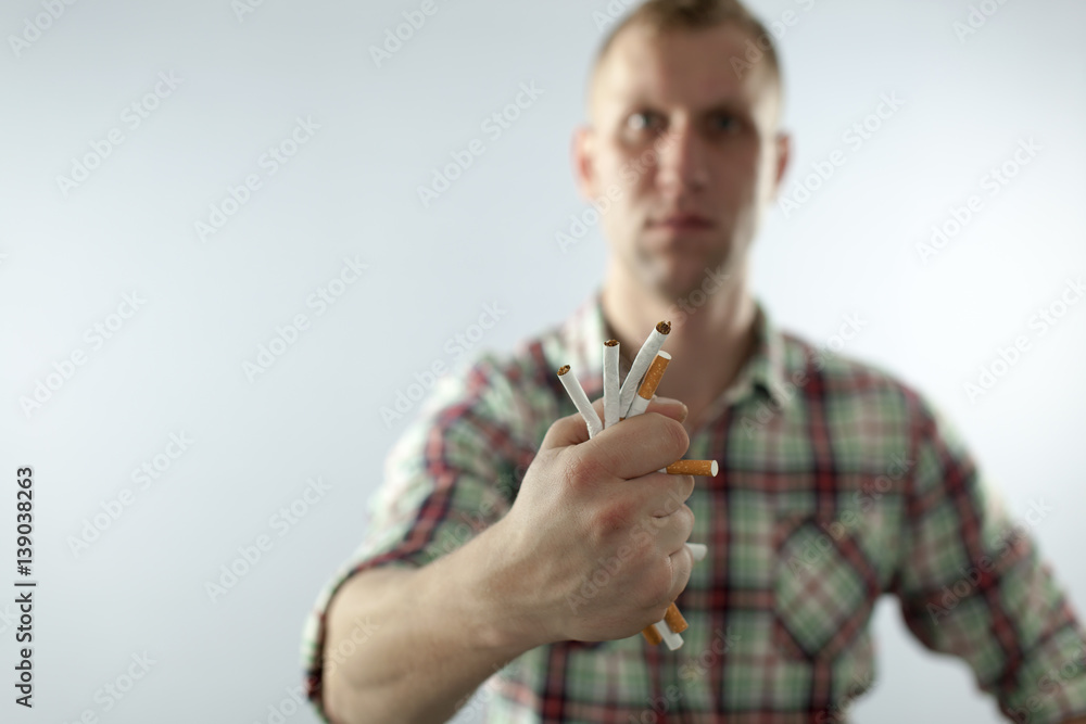 Man trying to quit smoking. Rumple cigarettes in hand Conceptual image.
Man trying to quit smoking. Rumple cigarettes in hand Conceptual image.