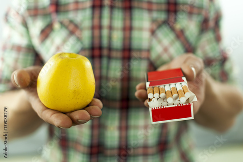 
Makes choice between  symbol of health like apple and tobacco Conceptual  cropped image. 
