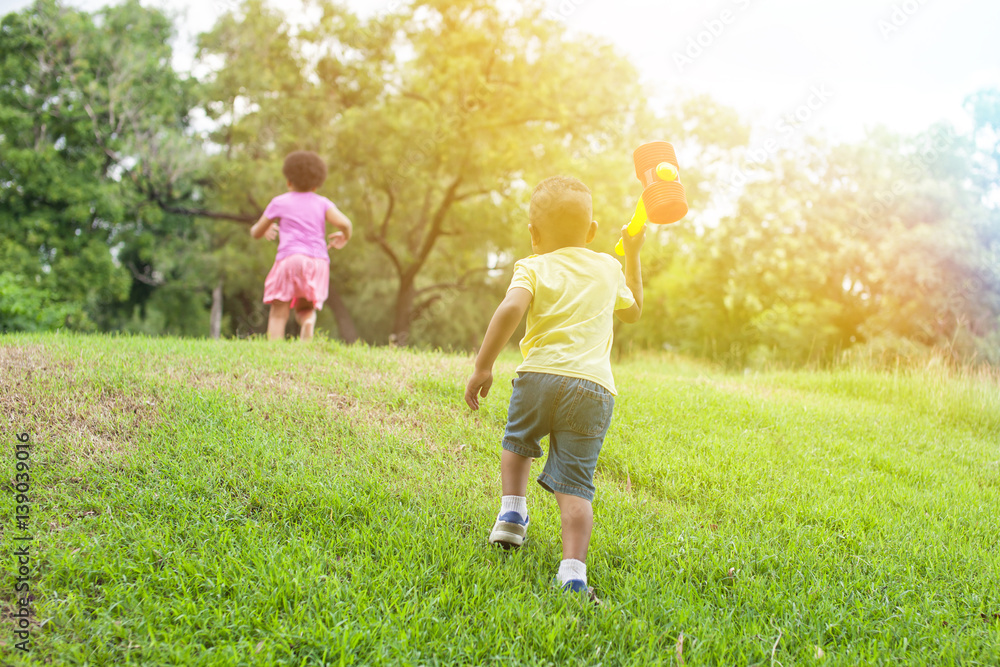 Fototapeta premium Kids running and chasing after each other in the green park in summer