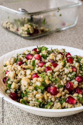 Wheat salad with pomegranate in white bowl.