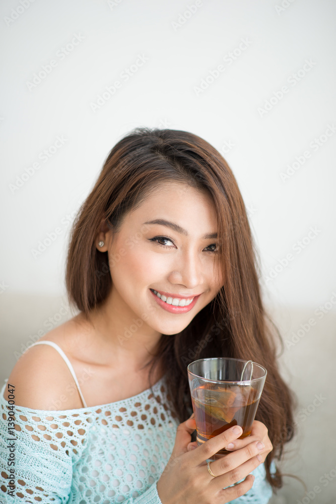 Beautiful young asian woman drinking her morning tea over a breakfast at home. Beautiful young asian woman drinking her morning tea over a breakfast at home.