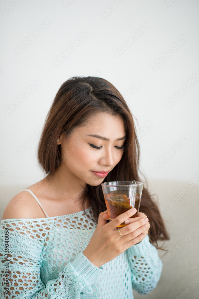 Beautiful young asian woman drinking her morning tea over a breakfast at home. Beautiful young asian woman drinking her morning tea over a breakfast at home.