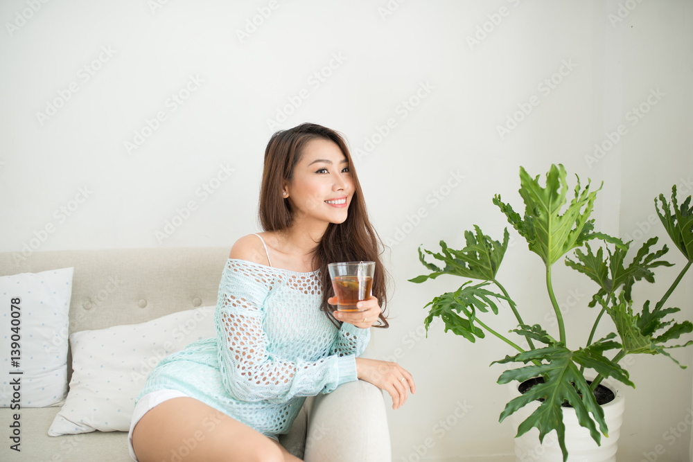 Beautiful young asian woman drinking her morning tea over a breakfast at home. Beautiful young asian woman drinking her morning tea over a breakfast at home.