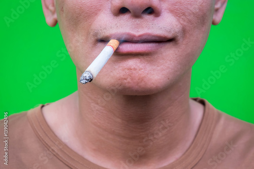 One asian man smoking on green background. Selective focus.