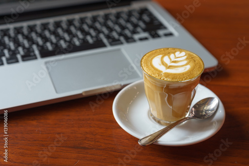 Breakfast with hot coffee latte and laptop in background on wooden table