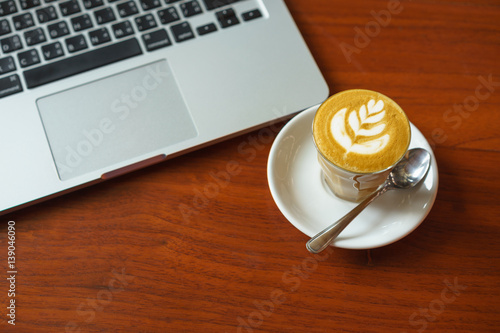 Breakfast with hot coffee latte and laptop in background on wooden table