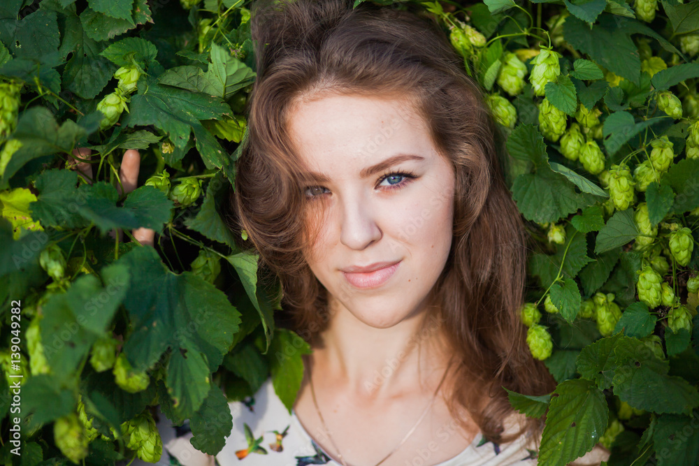 Young beautiful girl in fresh green branches of hop, warm summer day, closeup portrait Young beautiful girl in fresh green branches of hop, warm summer day, closeup portrait