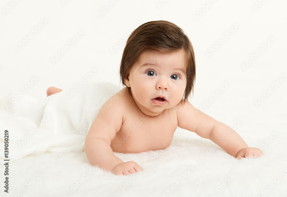 Adorably baby lie on towel in bed, white background. Happy childhood and healthcare concept. Yellow toned Adorably baby lie on towel in bed, white background. Happy childhood and healthcare concept. Yellow toned