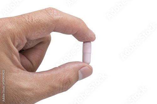 Hand holding a pink capsule pill isolated on white