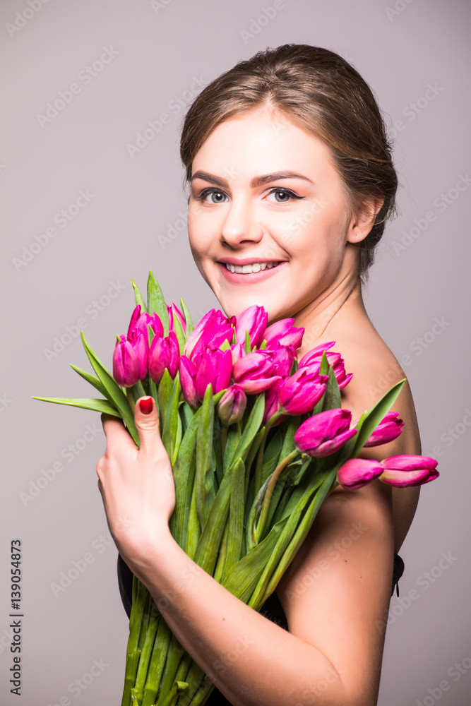 Beautiful girl with flowers tulips in hands on a light background