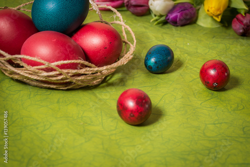 Easter eggs and tulips on green background