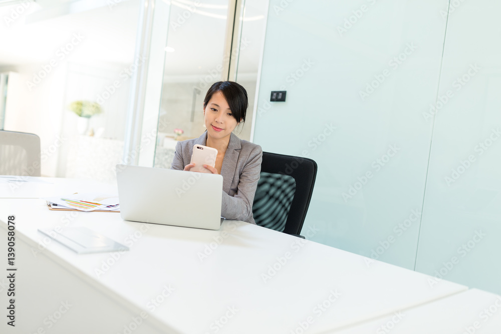 Business woman working on laptop and using cellphone in meeting room Business woman working on laptop and using cellphone in meeting room