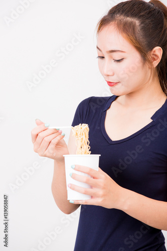 Young beautiful asian girl eating instant noodle using plastic fork.