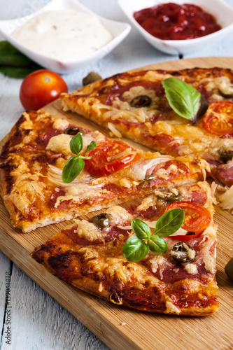 Slices of pizza with bacon, olives and tomatoes