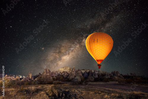 Hot air balloon flying over spectacular Cappadocia under the sky with milky way and shininng star at night