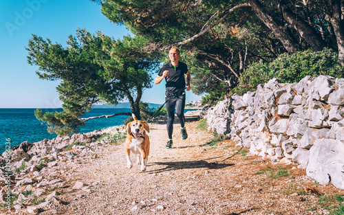 Man runs with dog near the sea photo