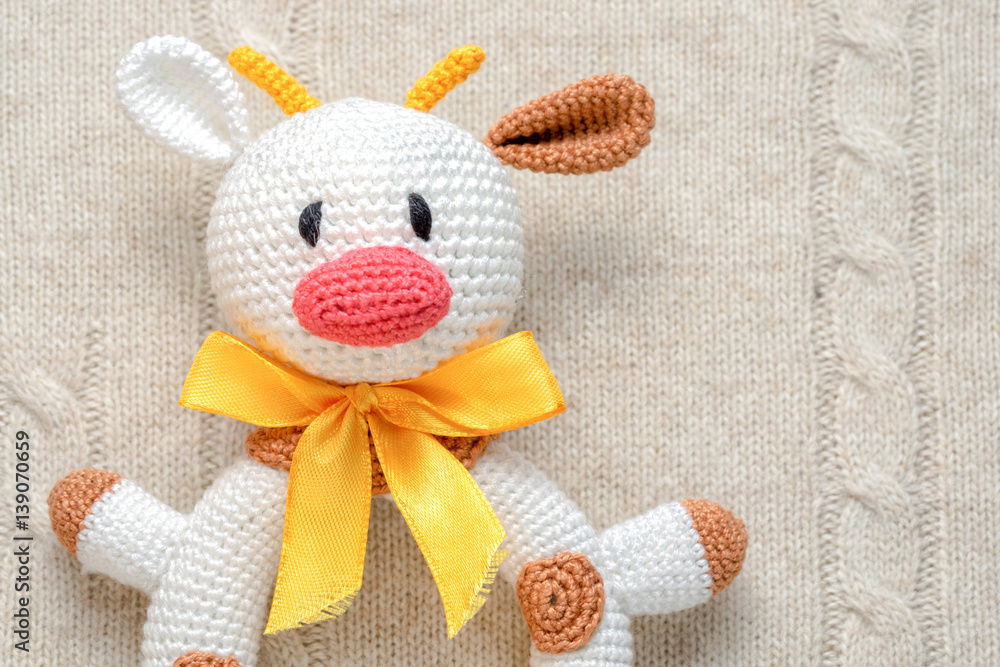 Fototapeta premium close up top view of amigurumi crochet bull toy on a knitted background with copy space