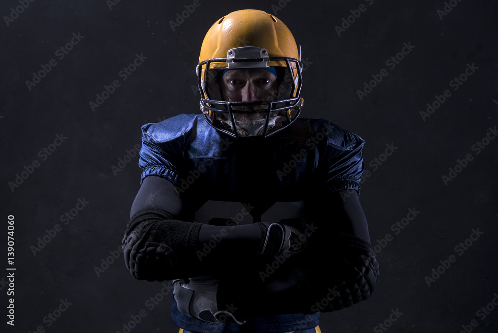 Portrait of Caucasian male american football player standing against dark background