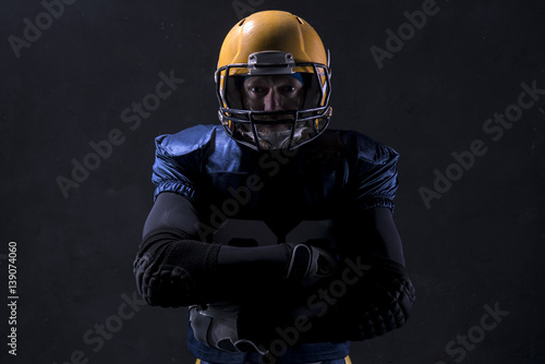 Portrait of Caucasian male american football player standing against dark background