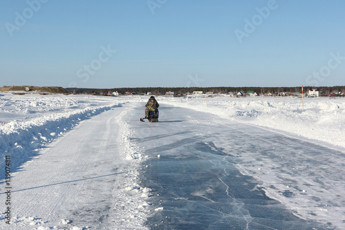 Snowmobile riding along ice road on a frozen reservoir in winter © Nataliia Makarova