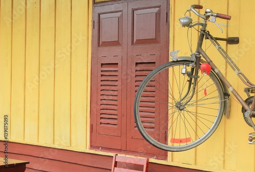 Vintage bicycle old style rusty on yellow wall  wood background.