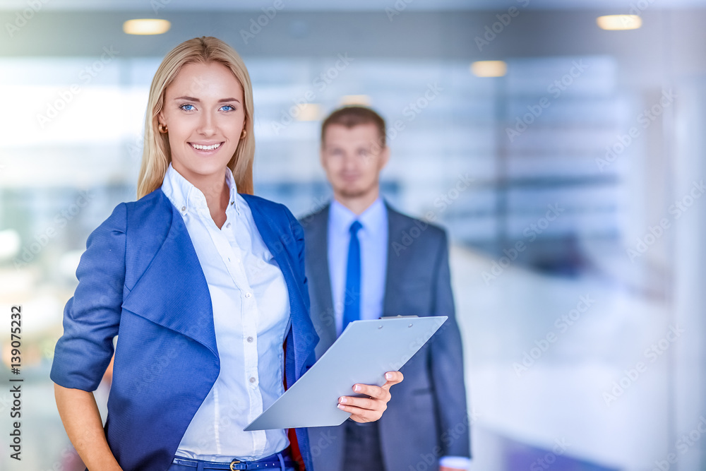 Portrait of young businesswoman in office with colleagues in the background Portrait of young businesswoman in office with colleagues in the background