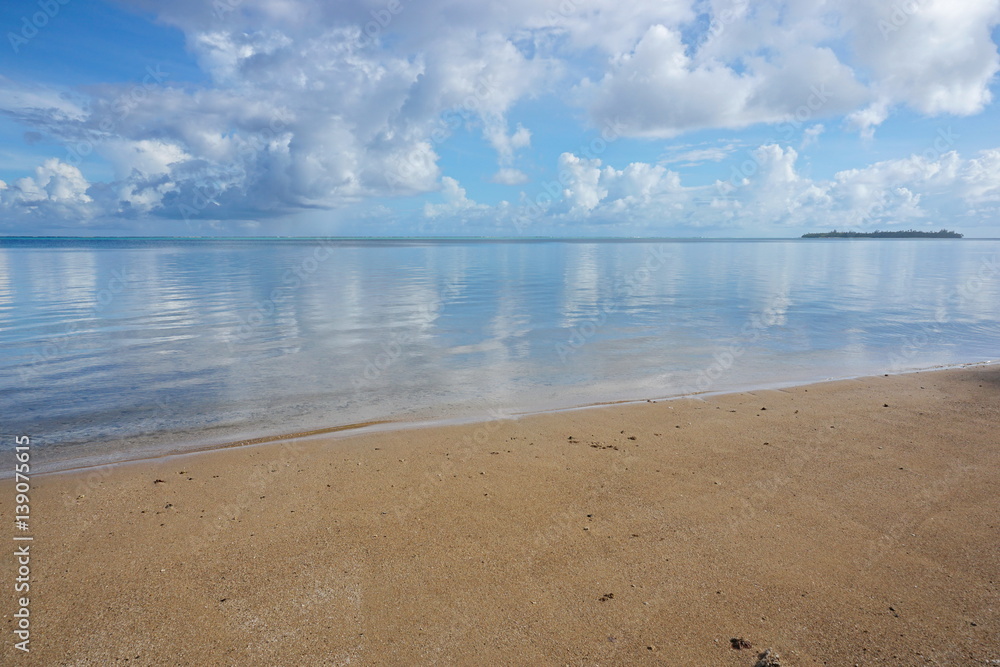 Peaceful seascape, calm water surface of a lagoon with beach sand in foreground, Huahine island, Pacific ocean, French Polynesia
