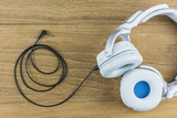 White headphones placed on a wooden backdrop.