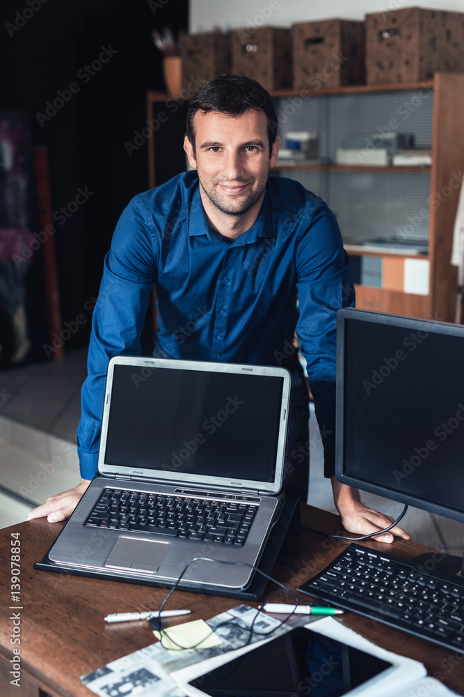 Smiling businessman standing at an office desk Smiling businessman standing at an office desk