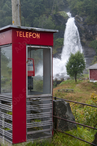 Waterfall and red telephonebox in green and beautiful nature. photo