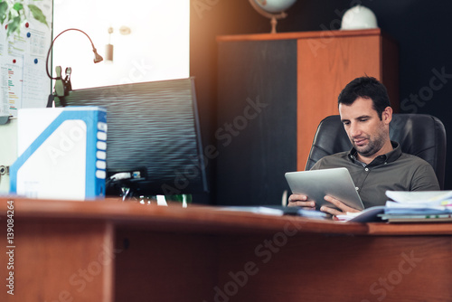 Businessman using a tablet at his office desk © mavoimages