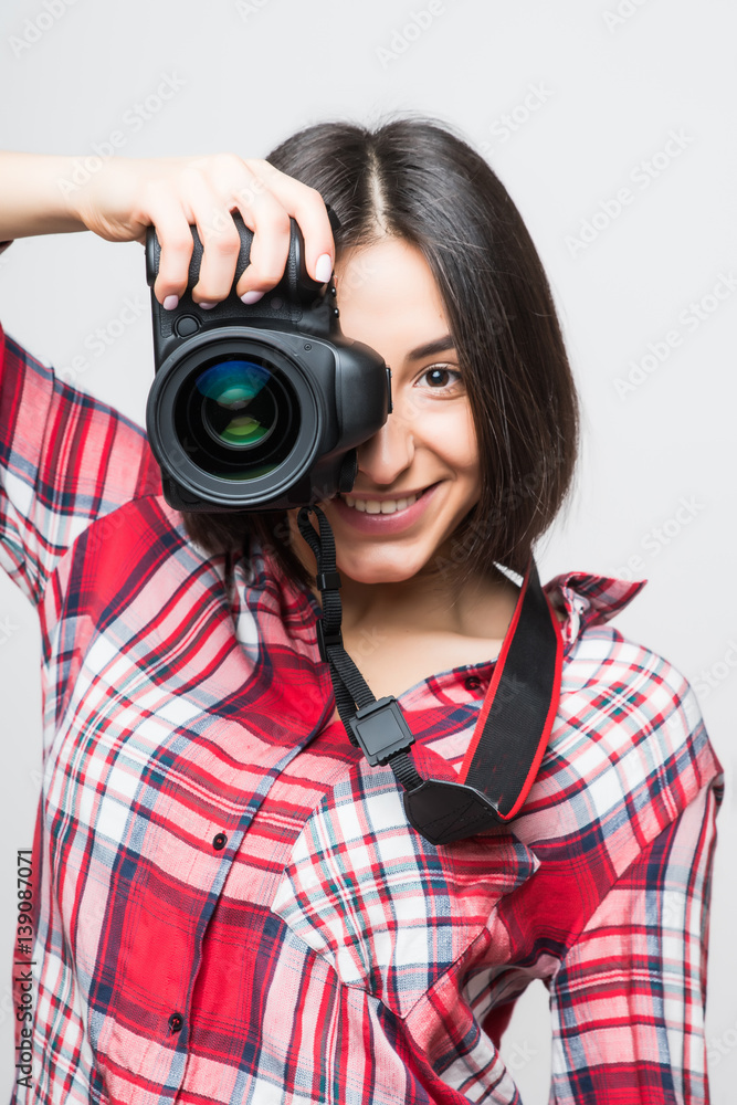 Woman photographer taking picture with camera on grey background Woman photographer taking picture with camera on grey background