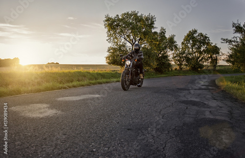 Fotografie Chopper rider, biker, driving on a road during beautiful sunset