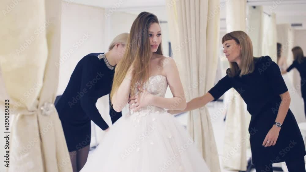 Pretty woman trying on wedding dress in fitting room Pretty woman trying on wedding dress in fitting room