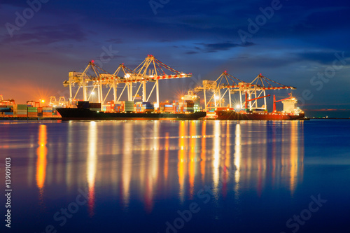 Containers loading by crane in the evening trade port shipping, Shipping and logistic concept