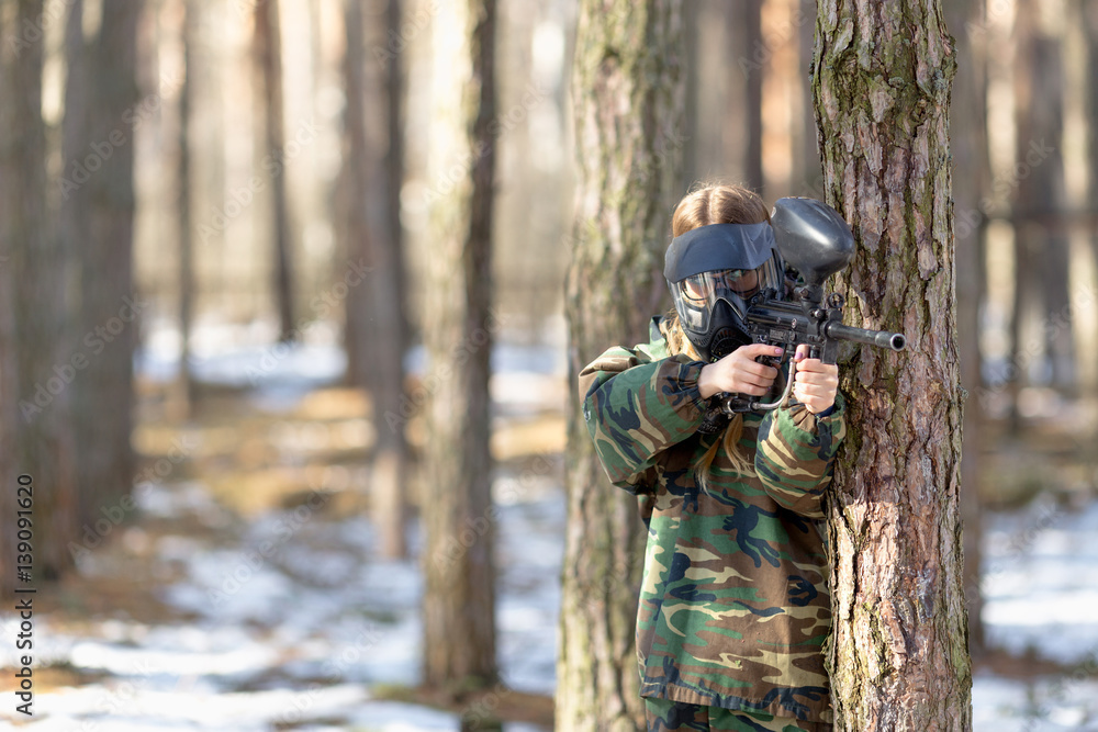 Fototapeta premium girl playing paintball in overalls with a gun.