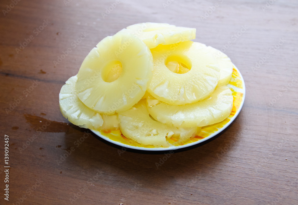 Canned pineapple on a plate on wooden table