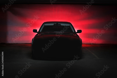 The car in the shadows with glowing lights in low light